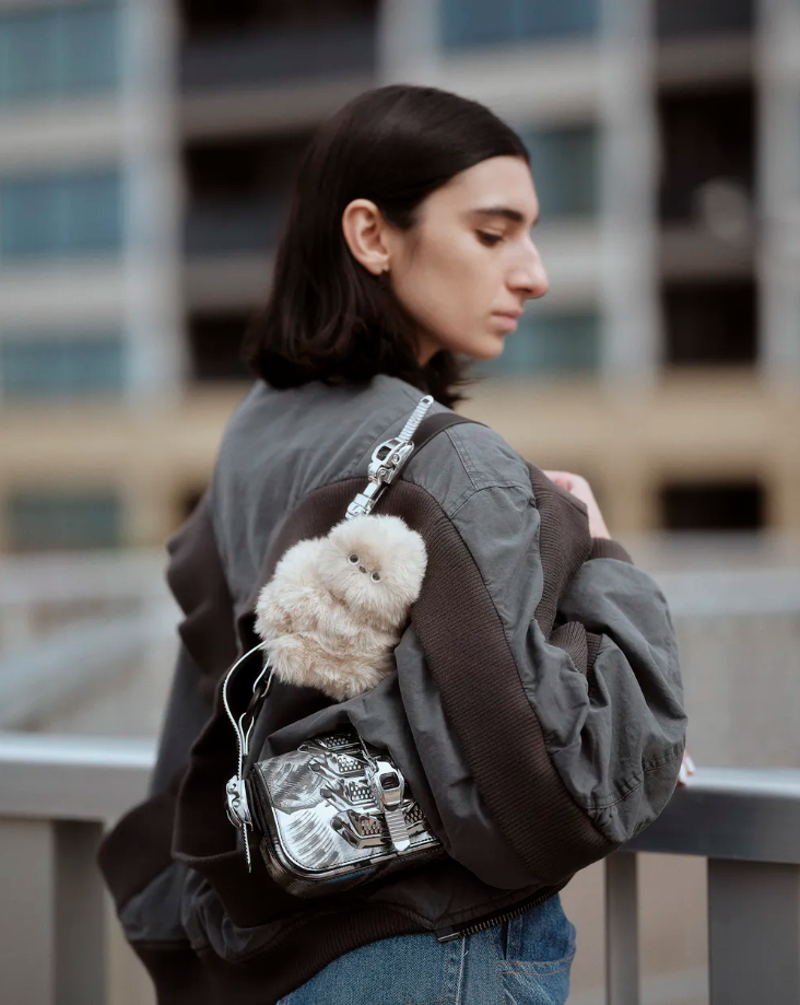 في ظل موجة الإكسسوارات التي تأتي لتزين الحقائب الرائجة خلال الآونة الأخيرة، يظهر اسم Mirumi في الواجهة لكن بتفاصيل تفاعلية أكثر من أي تصميم آخر.  ما هو Mirumi؟  Mirumi هو روبوت صغير، يمكن أن تضيفيه كإكسسوار على حقيبتك، يتفاعل مع الأصوات واللمس والحركة، ويلتفت بنظرات خجولة تخلق لحظات مفاجئة من الفرح. من خلال حركاته العفوية وتفاعله الطبيعي، يقدّم Mirumi تجربة مختلفة تقوم على الإحساس واللحظة، وليس على التعقيد أو الوظائف التقليدية. إكسسوار جميل بتفاصيل لافتة Mirumi يلاحظ العالم من حوله ويستدير لإلقاء نظرة. عندما تلتقي عيناه بعينيك، تشعر بلحظة من السعادة غير المتوقعة، مثل النظر المفاجئ لطفل صغير في مكان عام. ليس هذا فقط لك، بل يمكنه أن يجلب البهجة لمن حولك، فإذا كان مثبتاً على حقيبتك، قد يلتفت إلى شخص خلفك في القطار أو المكتب ويمنحه لحظة مفاجئة لطيفة. تفاعلاته الحية •	نظرات خجولة: يرمق من حوله وقد تلتقي عيناه بعينيك بشكل عفوي قبل أن ينظر بعيدًا، ليخلق لحظات صغيرة من الدفء. •	استجابة للمس: حساس في رأسه يكتشف التربيت، ويصدر ردود أفعال عشوائية وجذابة عبر خوارزمية خاصة. •	استجابة للأصوات: يدير رأسه باتجاه أي صوت أو صوت بشري، مظهراً الفضول والانتباه. •	حركة تلقائية: يتحرك أحياناً من تلقاء نفسه، مما يمنحه سلوك حي وطبيعي. تصميم ذكي وثابت صُمم Mirumi ليتمسك بإحكام بالحقائب، الأعمدة، أو أي أسطح ضيقة، ليبقى ثابتاً أثناء الحركة. يمكن وضعه على الحقيبة أو المكتب أو أي مكان آخر، وهو يظل يلفت الأنظار بسحره الصغير. رفيقك اليومي للبهجة Mirumi ليس مجرد لعبة أو ديكور، بل رفيق صغير يضيف لحظات فرح غير متوقعة في يومك. كل حركة، نظرة أو استجابة للمس تصنع تجربة لطيفة تشعر معها بالراحة والسرور.