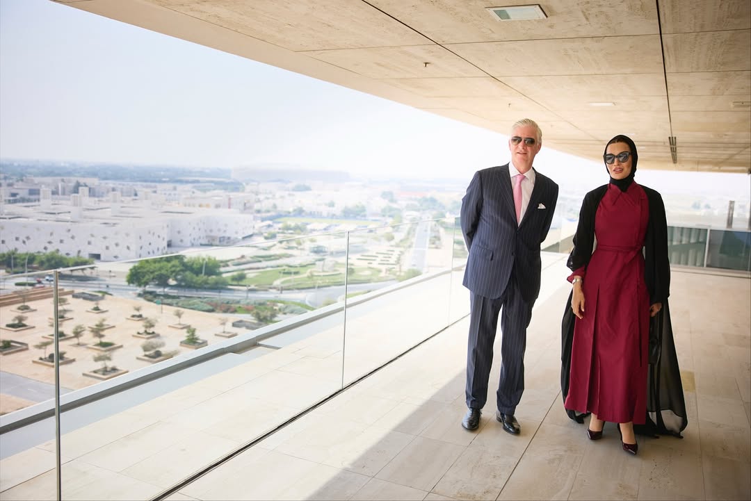 أثناء زيارة الملك فيليب، ملك بلجيكا، إلى مقر مؤسسة قطر وجامعة حمد بن خليفة، ظهرت سمو الشيخة موزا بنت ناصر بإطلالة أنيقة عكست الدقة في التفاصيل التي أتت مكملة لبعضها البعض.   الشيخة موزا بفستان بتصميم مخصص لها مع عباية سوداء  ارتدت الشيخة موزا فستان بتصميم خاص من المصمم الإسباني خوان فيدال Juan Vidal، مستوحى من مجموعته لخريف 2019، تميز بياقة كلاسيكية على شكل قميص مع تعديلات واضحة في القصة لتناسب أسلوبها المحافظ والأنيق. الفستان جاء باللون الأحمر البوردو وبقصة ضيقة عند الخصر وتنورة واسعة قليلاً بثنيات واضحة منحت الإطلالة حركة متوازنة. نسّقت سموّها الفستان مع عباية شفافة ووشاح أسود، ما أضفى تبايناً هادئاً بين الأحمر العميق والأسود الكلاسيكي، كما اختارت نظارات شمسية سوداء أكملت بها المظهر العام بطريقة عملية ومعبّرة عن الثقة. أما الحقيبة فكانت من دار روجيه فيفييه Roger Vivier، من طراز Choc Me  المصنوعة يدويًا من الجلد الطبيعي الأسود بتصميم مجعّد ومشبك معدني ثلاثي الأبعاد. يبلغ سعرها نحو 3995 دولار، وتجمع بين الطابع العملي والتفاصيل الحرفية الدقيقة التي تشتهر بها الدار. في ما يخص الإطلالة الجمالية، اختارت سمو الشيخة موزة مكياجًا ناعمًا بلمسات برونزية دافئة، مع لون شفاه يعزز إشراقة البشرة ويكمل توازن الإطلالة.