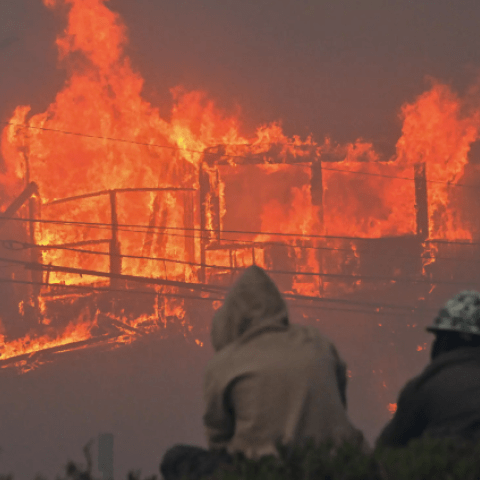 رجال يشاهدون منزلاً تلتهمه النيران بسبب حريق &quot;باليسيدز&quot;  © أ ف ب